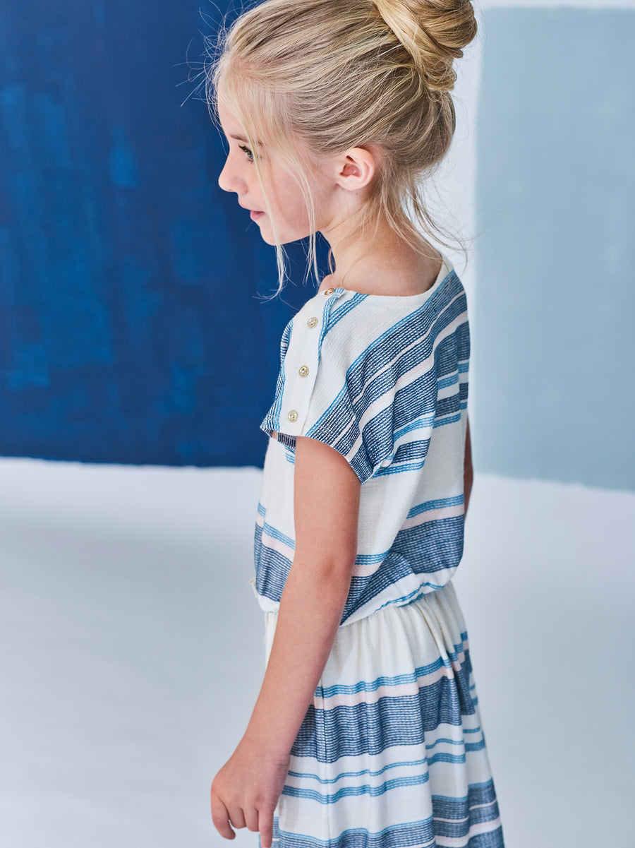 ecru jacquard dress is striped with turquoise blue, pale pink and jade. Its fluid and light material is very flexible. The silhouette is bent by an elastic at the waist, enhanced by a golden lurex knot. By Jean Bourget.