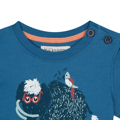 Blue cotton jersey t-shirt printed with a mammoth adorned with glasses on the front. Two buttons placed on the left shoulder. By Jean Bourget.