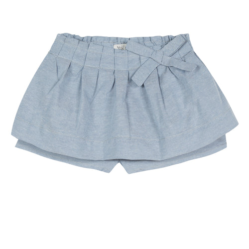 Light blue chambray skort is animated with elegant flat pleats on the waist, bringing a puffing effect to the silhouette. Designed by Jean Bourget.
