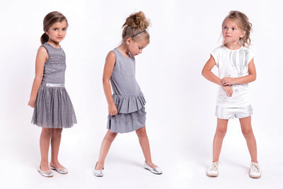Little girls sleeveless grey party dress with a tutu skirt and shimmer throughout. A silver strap lines the waist for finished look. Dress made by Imoga.