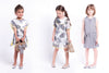 Grey sleeveless dress with feather designs all over and the sides are lined with yellow pom pom balls. By Imoga.