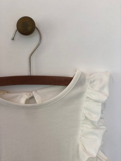 Girls sleeveless ivory tank top with ruffles lining both sides. Shop Vignette for girls.